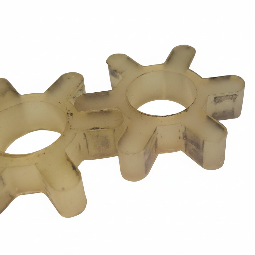 Two translucent off-white elastomer gear-like components with dark smudges, resting on a white surface.