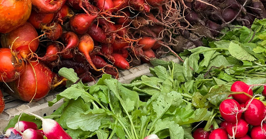 A colorful variety of fresh root vegetables including radishes, beets, and carrots at a local market.