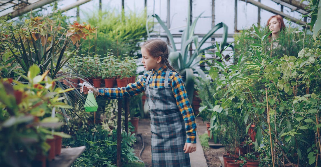 A child waters plants in a vibrant indoor greenhouse setting.